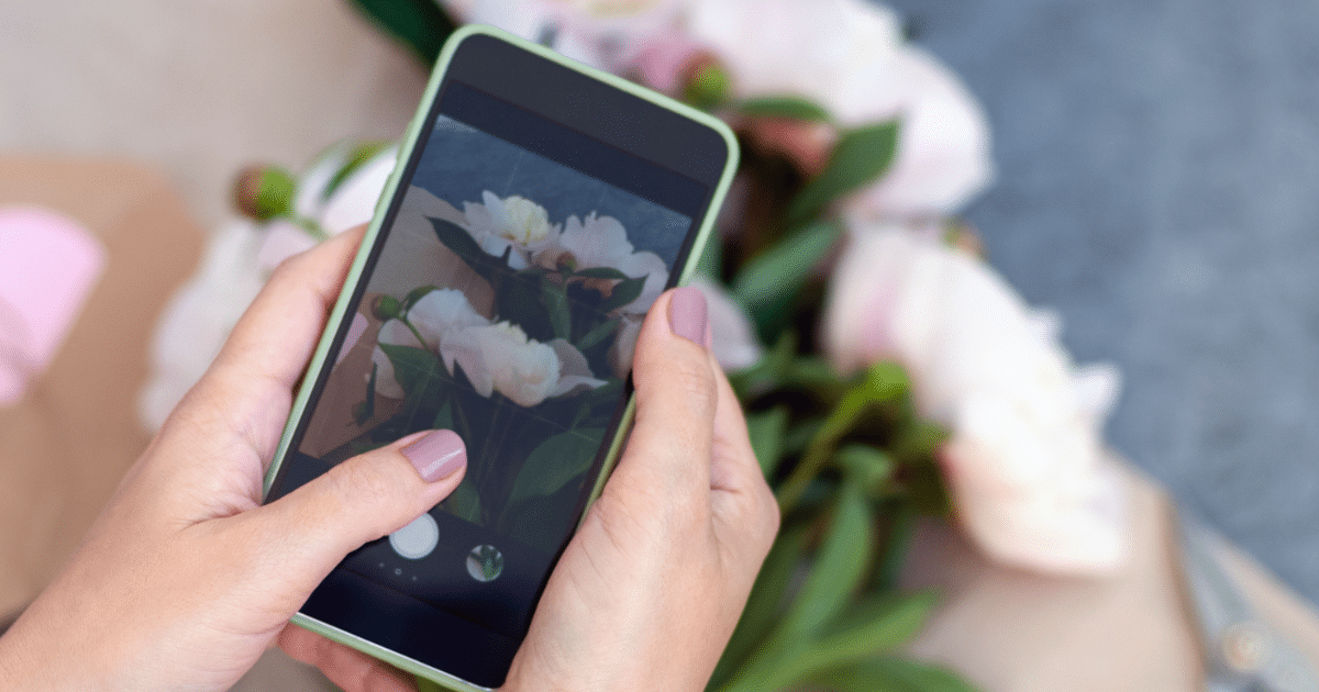small business woman taking picture of flowers for facebook