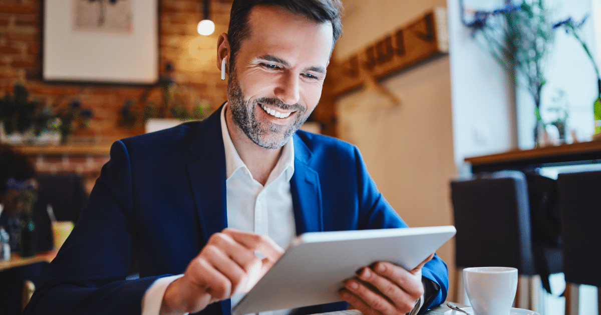 male professional looking at tablet and smiling with airpods in