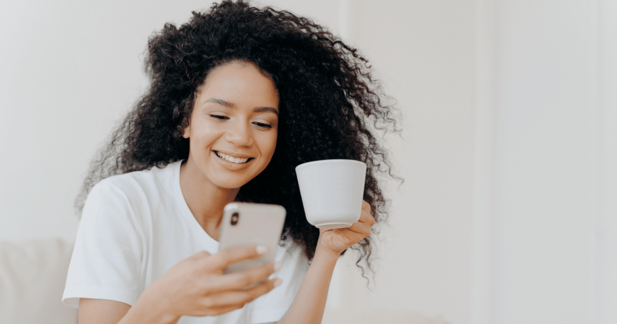 female holding coffee cup and looking at cellphone