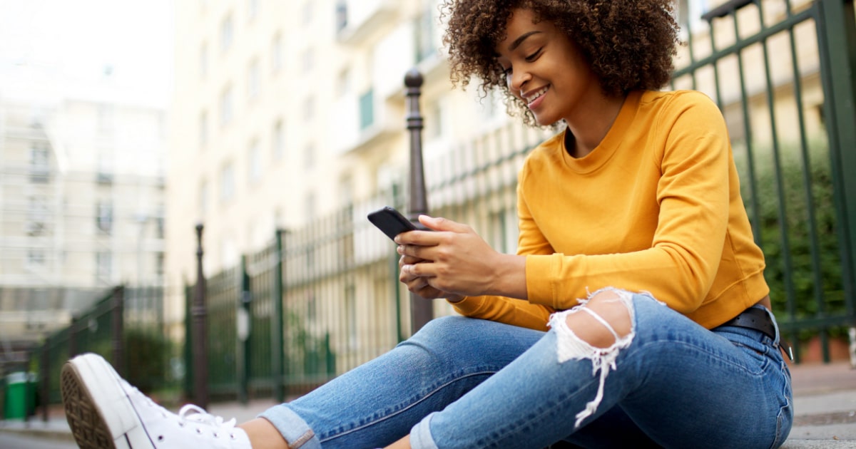 female sitting outside scrolling social media on her phone
